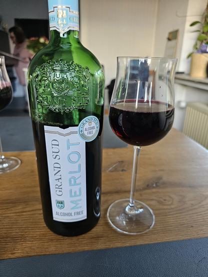 Das Bild zeigt eine grüne Flasche Wein mit der Aufschrift "GRAND SUD MERLOT" und "ALCOHOL FREE" auf einem Holztisch. Die Flasche hat ein elegantes Design mit einem Siegel, das "GRAND SUD" und "ALCOHOL FREE" zeigt. Neben der Flasche steht ein Weinglas, das halb gefüllt mit dunklem Rotwein ist. Im Hintergrund ist ein Teil eines Raumes zu sehen, mit einem weiteren Weinglas und einer Person, die im Hintergrund steht. Die Flasche und das Glas sind zentral im Bild und liegen auf einem dunkelblauen Tischdeckenstück.

Bereitgestellt von @altbot, privat und lokal generiert mit Ovis2-8B