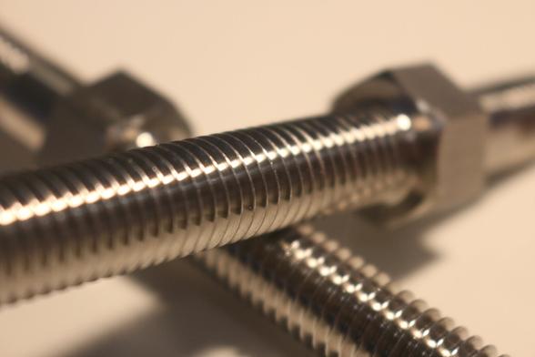 Image shows to threaded bolts lying one on top of the other at crossed angles. Background is a yellowing white.