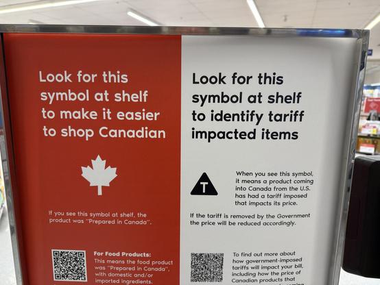 A sign in a store explaining two symbols to shoppers: one for identifying Canadian products, indicated by a maple leaf, and another for items impacted by tariffs from the U.S., marked with a "T" symbol. The sign also includes QR codes for more details.