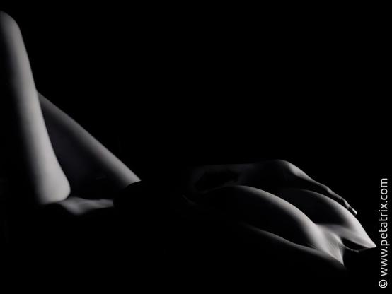 Female nude photography, lying torso, breasts and pubic hair are covered, black and white photography, sidelight with pronounced shadows