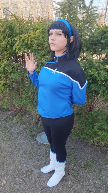 A cosplayer of the character T'Lyn of the tv show Star Trek: Lower Decks standing in front of a hedge.