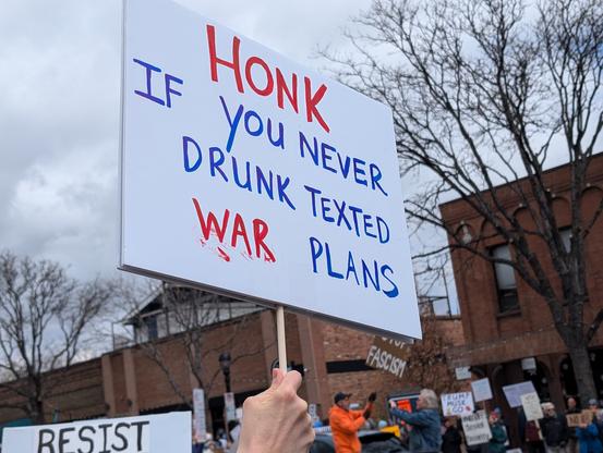 Protest sign "honk if you never drunk texted war plans"
