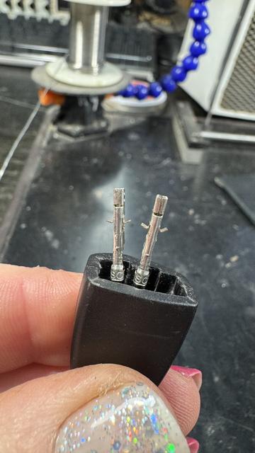 Close up on two damaged female ATX plug sockets, their long, shiny, metal, rectangular bodies looking very much like twin Ned Kellys with arms out in shrug of unknowing.