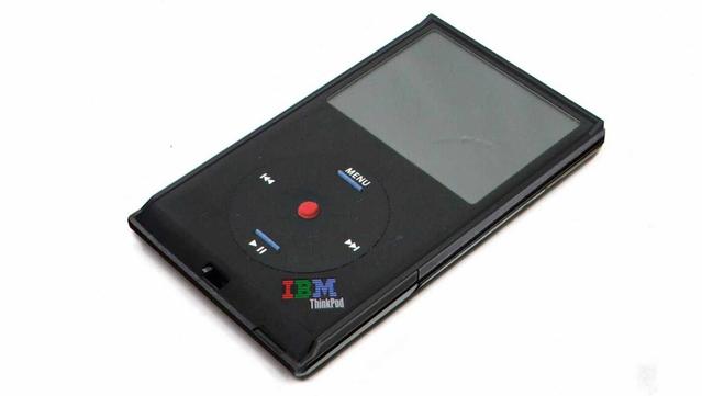 A fake render of an "IBM ThinkPod Classic", which is a parody of an iPod classic but with ThinkPad black plastic case, the clickwheel replaced with directional buttons incl. ThinkVantage blue nubs and a "red dot" trackpoint, next to ThinkPad-esque curvature at the bottom and a "IBM ThinkPod" lettering at the bottom right corner like from a classic ThinkPad