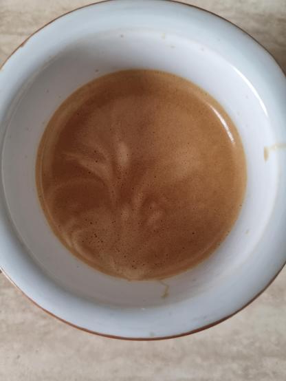 In una tazza bianca, sulla superficie del caffè sembra disegnato un giglio