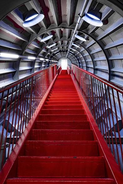 Look-up view on red metallic stairs linking two of the spheres of tha Atomium in Brussels. The Atomium is a Landmark modernist building in Brussels, Belgium, originally constructed as the centrepiece of the 1958 Brussels World's Fair (Expo 58). The Atomium stands 102 metres (335 ft) tall, making it one of the tallest structures in Belgium. Its nine 18-metre-diameter (59 ft) stainless steel clad spheres are connected in the shape of a unit cell that could represent an iron crystal magnified 165 billion times Steel tubes connecting the spheres enclose stairs, escalators and an lift (in the central, vertical tube).