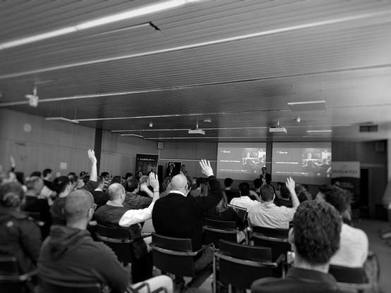 Black and white photo of developers raising hands at a hackathon