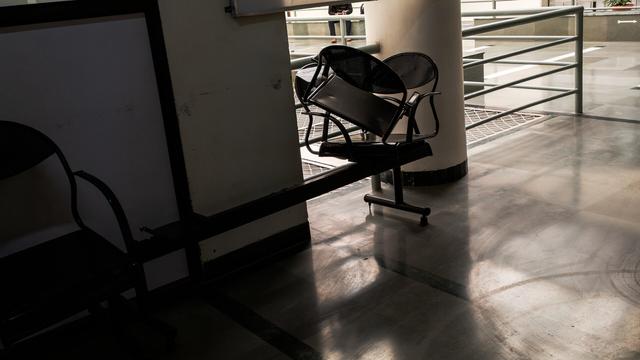A photo of two chairs sitting in a third chair. The chairs are painted black and made out of metal, and should be affixed on the metal base below them. To the bottom left of the image, there is another black metal chair. To the top right of the image, there is a grey metal railing.