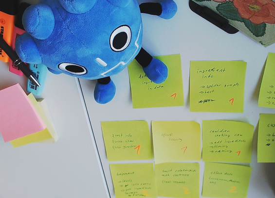 A godot plushie sitting on a desk, surrounded by sticky notes with to-dos