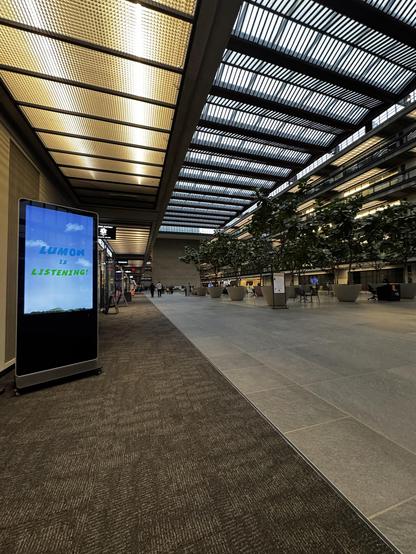 The East atrium of Bell Works with a sign saying “alumni is listening”.