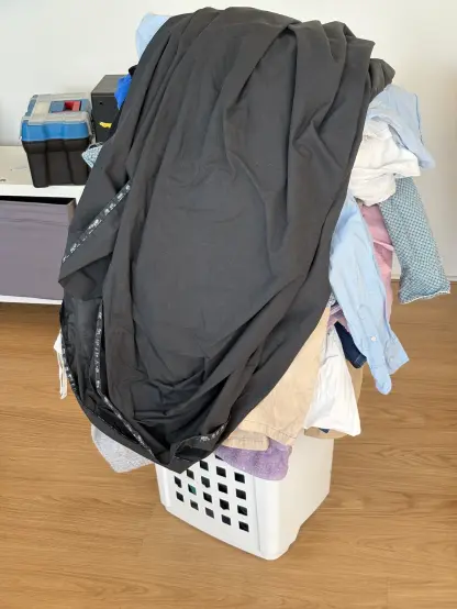 A large white laundry basket overflowing with laundry