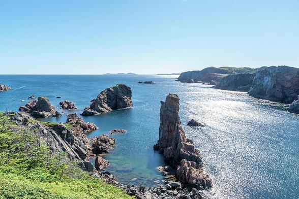 A view of Spiller's Cove near Twillingate, Newfoundland, as seen from the top of one of the cliffs surrounding it, on a beautiful sunny day.