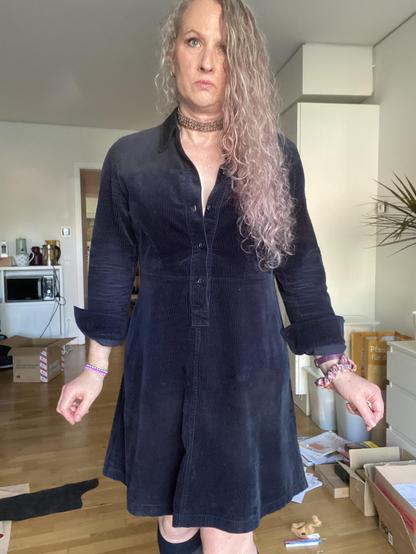 Elodie is a 50 something trans girl, here wearing a navy corduroy dress, and navy knee high socks