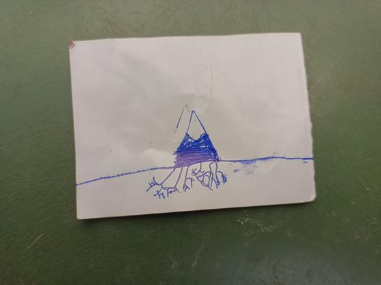 Dessin d'enfant au stylo bic sur un mini bout de papier : un triangle bleu avec un sommet enneigé, posé sur un trait (le sol), et sous cette ligne, plein de petit traits qui se divisent, comme plein de petites racines