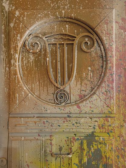 Porte de la villa de l'expo Layup, recouverte de projections de peinture, avec un bas relief représentant une lyre