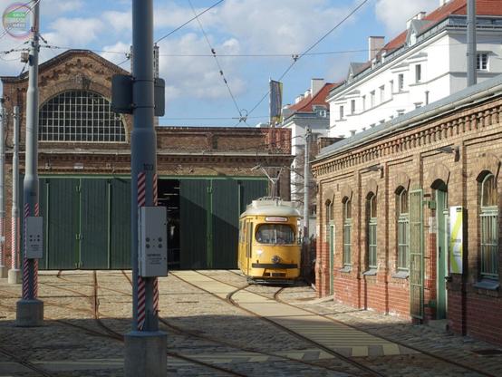 Alte Straßenbahnremise mit gelbem Arbeitsstraßenbahnwagen davor