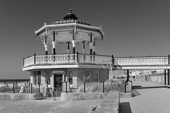 Monochrome photo of a Victorian, oriental-style bandstand facing Brighton beach.