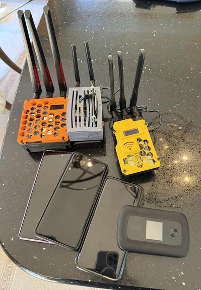 Far too many wardrive rigs and phones are laid out on a shiny black countertop