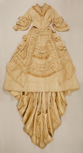 The same gown, shown to be ivory-colored, laid out flat on a surface.