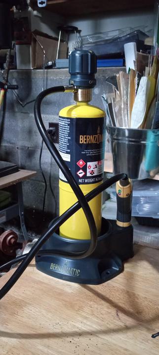 A propane/MAP gas canister stand with 41 inch hose and trigger for brazing metal. The hose connects directly to the gas canister and the trigger lights the gas, has an adjustment for flow and makes it easier to aim the flame at the object one is trying to heat. The trigger has an approximately 4 inch steel nozzle to aim the flame.