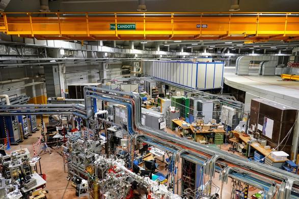 A lot of scientific equipment, like computers, tubes etc., inside synchrotron experimental hall, viewed from above.