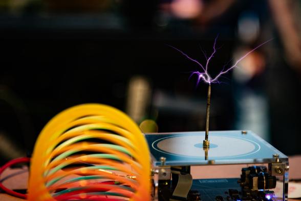 Color photo of a small tesla coil with brush discharge emanating from a needle-like electrode.