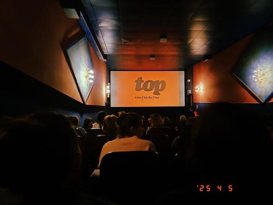 A crowded ci ema right before the start of the film with the screen centred.