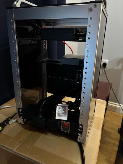 A rear view of the mini rack, the same equipment from the rear can be seen as installed on the front (refer to other image) at the bottom a rack mounted extension lead is installed with two plugs out of three attached. To the right hand side of the plug is a red switch can be seen, it is currently turned off