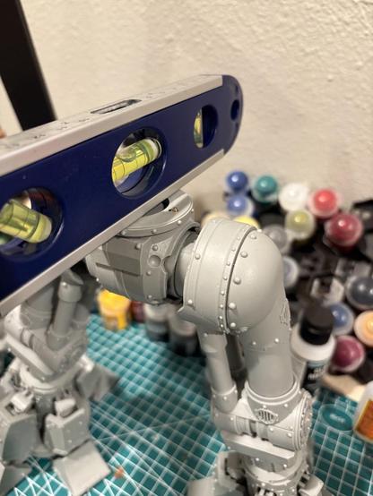 The top of the Reaver Titan’s legs, now attached with a waist piece. A level sits on top of them, demonstrating that at least along that axis, they are level. A small pin can just be seen poking out of the top of the waist.