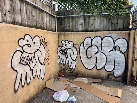 A few graffiti tags spray painted in a storage section behind an empty store in San Francisco. Two of the tags are of Ribity’s unique frog character. The other tag simply says “GK” in large bubble letters. The tags are all two-color throw ups with a white base layer and black outlines.