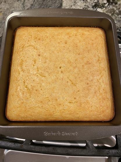 mottled yellow and light brown cornbread still in its pan, out and on a stovetop to cool