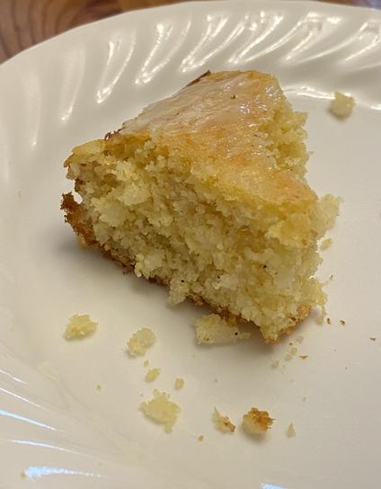 a piece of the cornbread on a white plate, partially eaten, with a bit of butter on top.