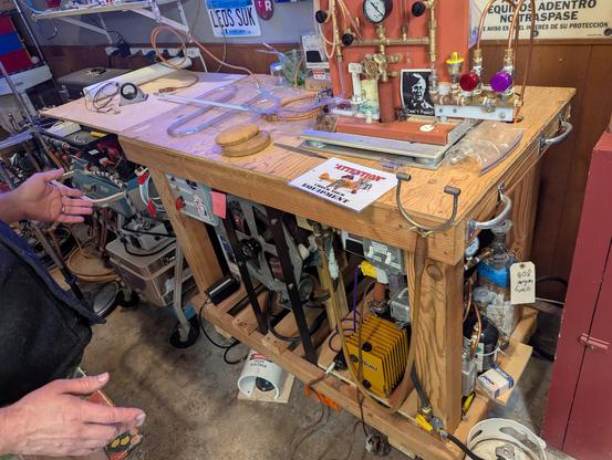 Robert Haus' bombarding table, made of wood, with vintage hand torch and a brass manifold. He has a giant variac under the table that is used as a choke for a 7.5kva bombarder coil. Unlike most bombarding systems, this lets him turn it down all the way to less than a normal neon transformer current.