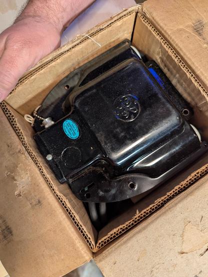 A black GE window hanging transformer still new in box. You dont see this style (or brand) of transformer around hardly anymore. Robert would know for sure, but I would say its fromthe 1940s. Blue UL sticker on the side of it,
