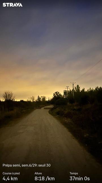 Chemin de terre sous un ciel faiblement éclairé par le ciel levant. Des statistiques Strava sont visibles.