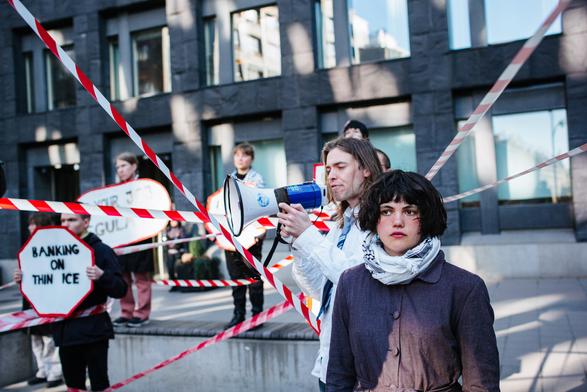 Protesters between red & white emergency tape and one person can be seen with the loud speaker.