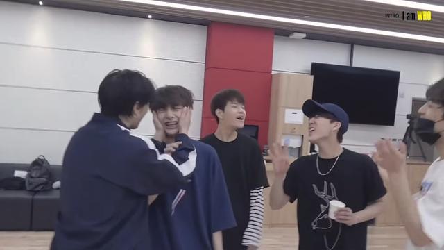 skz members in a dance practice studio. Hyunjin is squishing I.N's face between his hands. Seungmin and Changbin are enthusiatically appreciating the moment.
