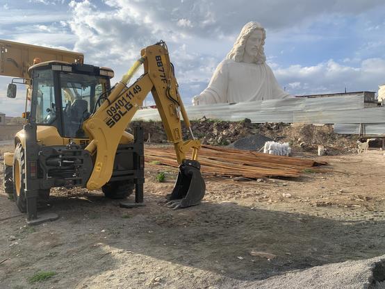 Huge Jesus statue, temporarily grounded amidst construction site.