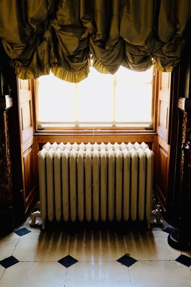 An old radiator next to a window with soft light coming in, a warm tone and marble floors at Blenheim Palace
