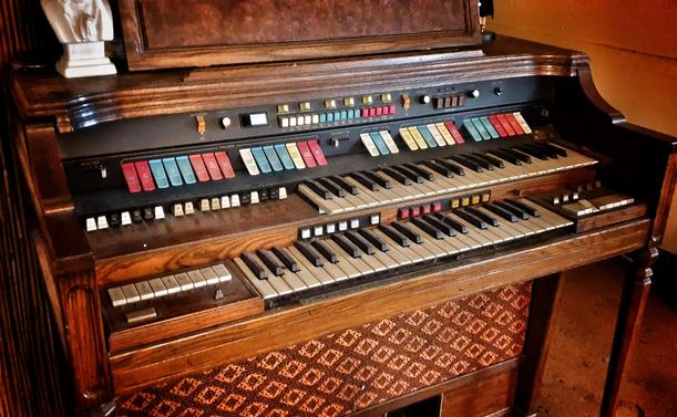 Foto mit leichtem HDR-Filter und Vignette. 

Eine alte Orgel aus massivem Holz mit vielen bunten Knöpfen und Ziehdingern...und schwarzweißen Tasten. 
Register, oder so. 

Oben drauf steht ein Gipskopf von Beethoven. Der wird eigentlich nicht verschenkt, aber...who knows.