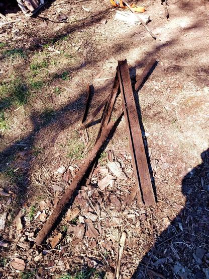 A pile of freshly excavated steel scrap. A relatively straight angle iron, one bent or welded into a U-shape, a large pipe filled with soil and an I-beam almost 1m long.