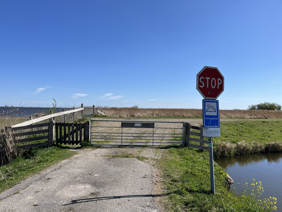 The end of a road, with a closed gate. On the right is a stop sign visible which should not be used in this situation.