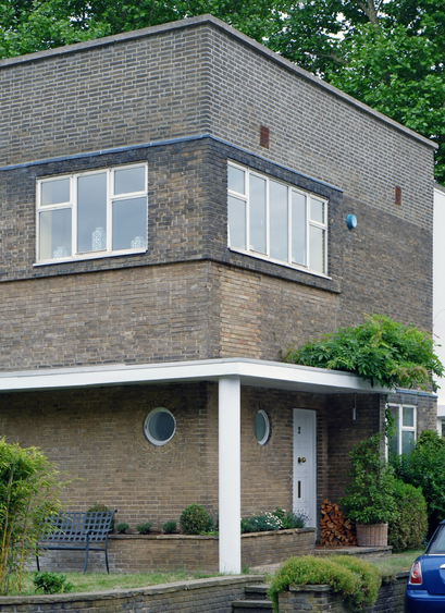 A colour photograph of the corner of a modernist house in Frognal Close with a flat roof and porthole window