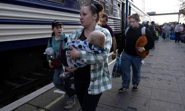 Una mujer lleva en brazos a su hijo de 16 meses mientras su familia se dirige a un tren de refugiados en octubre de 2024 en Pavlohrad, Ucrania. (Paula Bronstein/Getty Images)