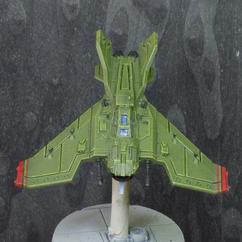 Photo of a painted miniature of a lightning voss jet fighter from warhammer. It's painted medium green, has red stripes on the wing tips