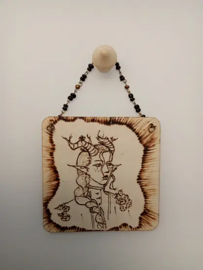 Un tableau carré en bois pyrogravé d'un portrait d'une tête de personnage fantaisie