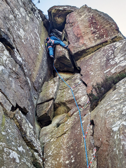 Rock climber nearing the top of a sandstone crag.