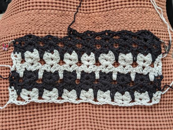 cat stitch scarf in alternating black and white, on a brown waffle-knit towel - three rows of stitches makes one row of cats!