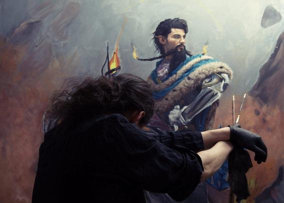 photo of a man with long hair standing in front of an oil painting in dramatic light with his head hanging down and his arms supported.