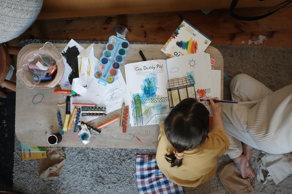 A child next to her mum drawing on a coffee table